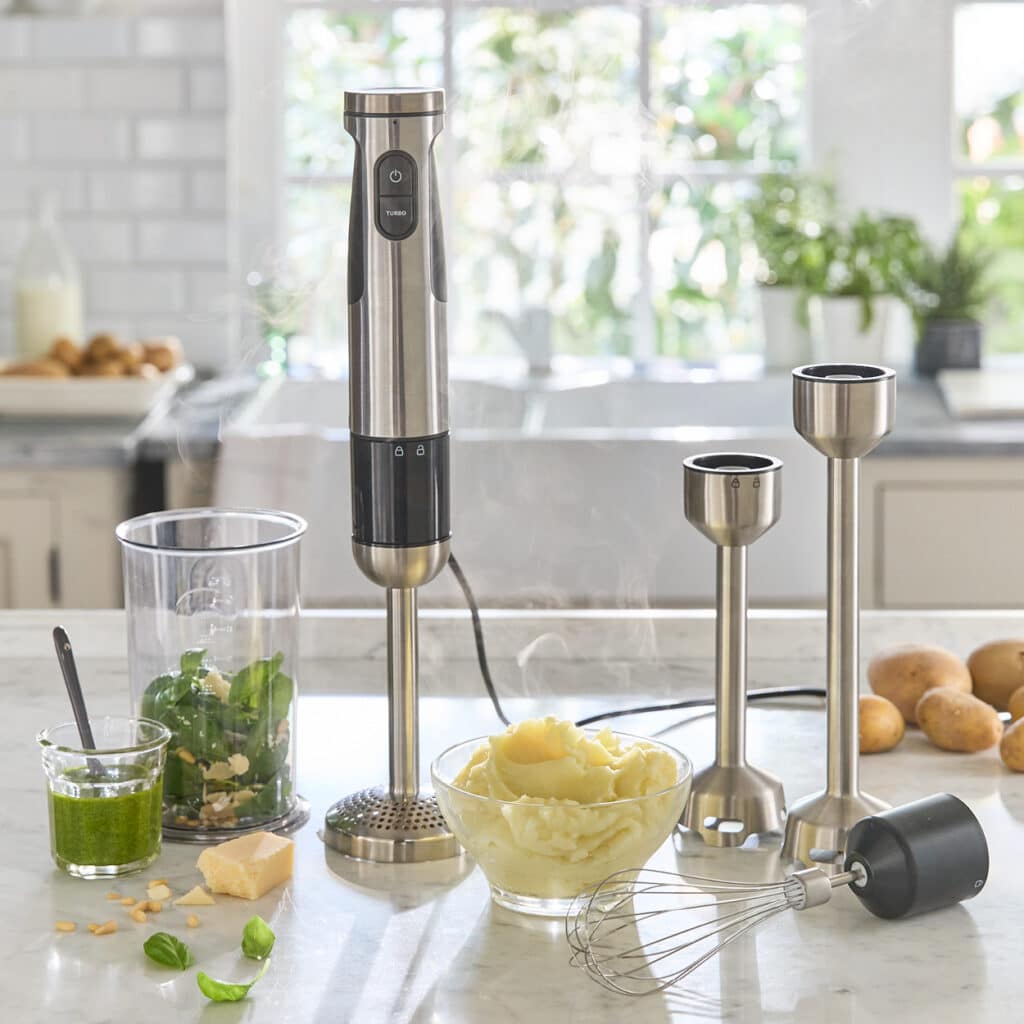 Stabmixer mit verschiedenen Aufsätzen, dazu Pesto, frische Kräuter, Kartoffelpüree und Zutaten.