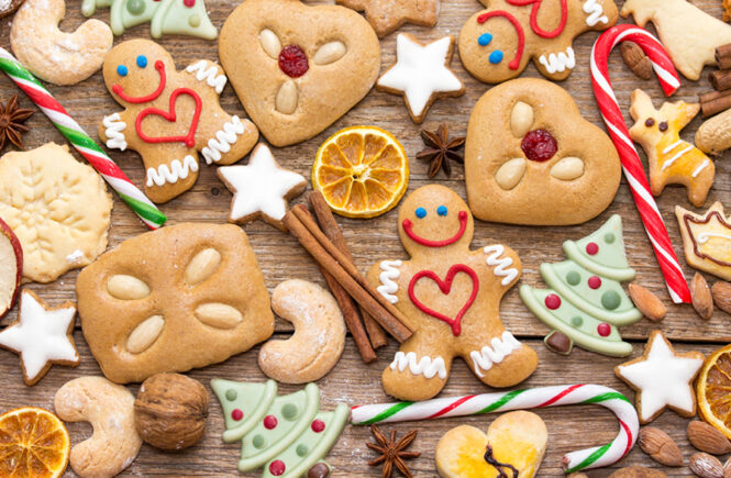 Weihnachtlicher Plätzchen-Mix aus Lebkuchen, Zimtsternen, Zuckerstangen und getrockneten Orangenscheiben auf rustikalem Holz.