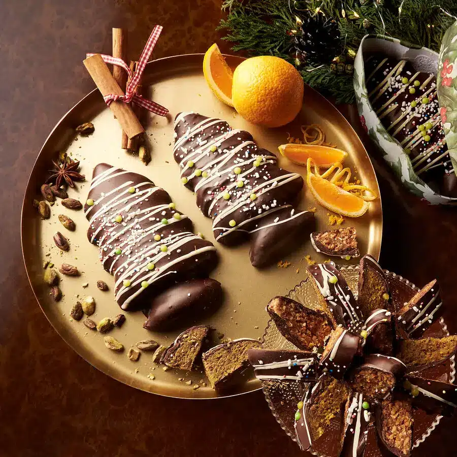 Mit Schokolade überzogene Lebkuchenbäume mit Pistazien, Orangenzesten und Zimt, weihnachtlich serviert