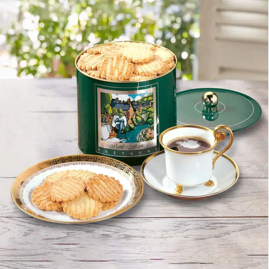 Französische Butterkekse in grüner Blechdose, serviert mit Kaffee in Porzellantasse auf goldverziertem Teller