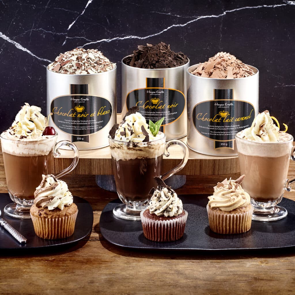 Trinkschokolade Hagen Grote in Sorten Chocolat noir, Chocolat au Lait Caramel, verfeinert mit Cupcakes und Sahne.