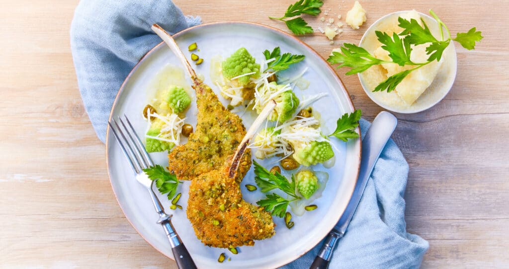 Magret de canard ros&eacute; tranch&eacute;, servi avec une pur&eacute;e de l&eacute;gumes et une sauce brune, d&eacute;cor&eacute; d&rsquo;herbes et de fleurs comestibles sur une grande assiette blanche.