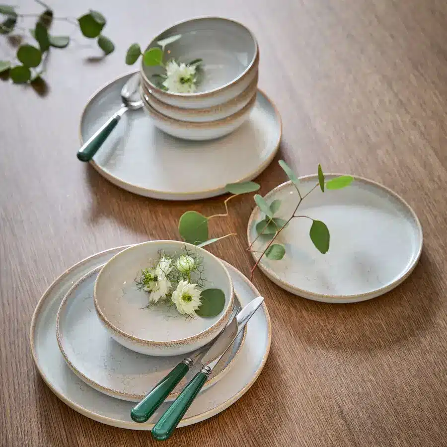 Vaisselle en grès clair dressée sur une table en bois pour la table de Pâques